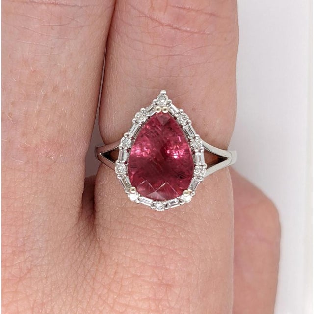 A pink tourmaline glows in a bright pink at the centre of this solid 14K white gold ring, accented with earth-mined...