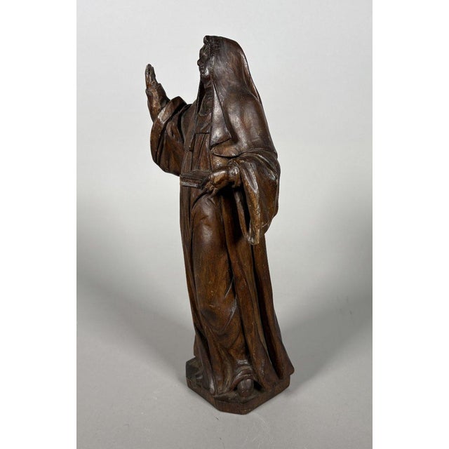 Saint Anne or Saint Bridget, carved wood with a brown patina. French work, 17th century. She is depicted with one hand...