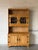 This striking oak hutch features upper glass doors with leaded details, open display shelving, and an enclosed lower...