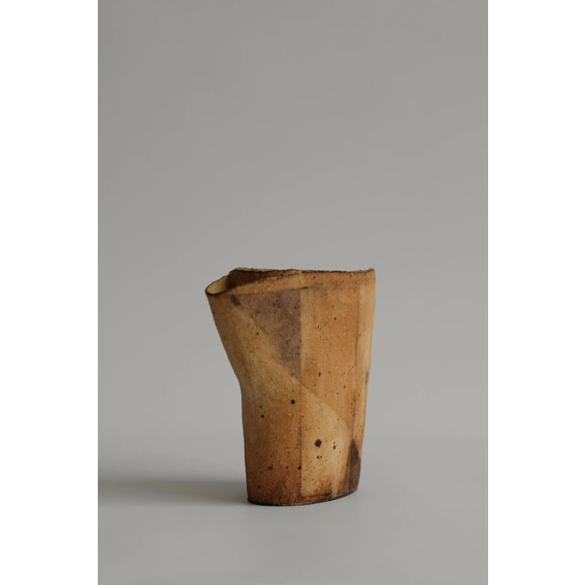 A sculptural ceramic vessel / pitcher with an asymmetrical, flared rim. Its faceted motif emerges through the firing...