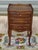 Elegant bedside table with three drawers and raised edges on three sides of the top. Tall, slender legs with cabriole...