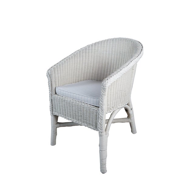 Two vintage white wicker arm chairs featuring a woven and braided design with sloped arms and striped seat cushions....