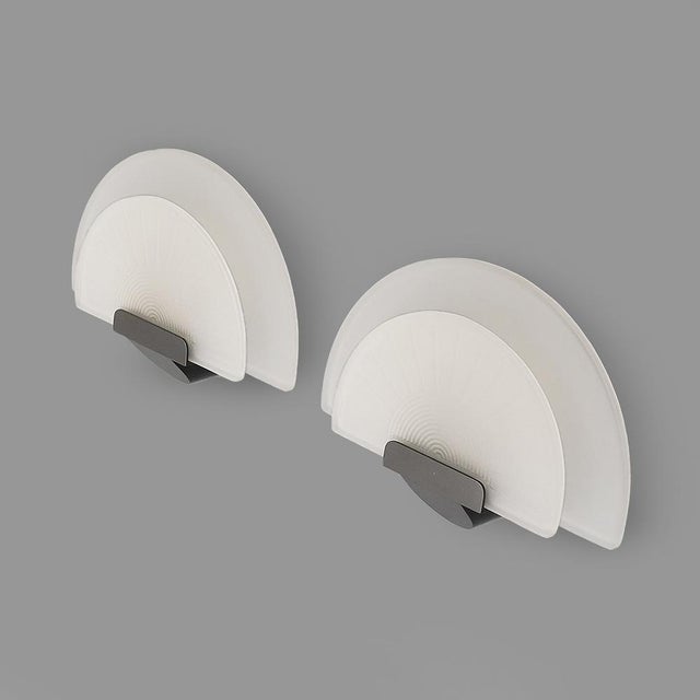 Pair of wall lamps produced by Arteluce in the 1980s, designed by Ezio Didone. The structure is made of metal painted in...