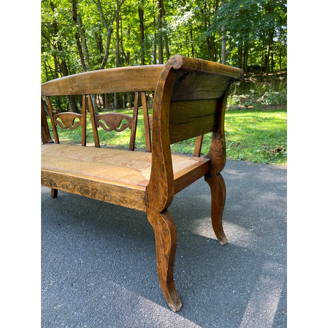 Beautiful early 19th century European bench crafted in solid elm with a handwoven rush seat. Features elegant rolled arms,...
