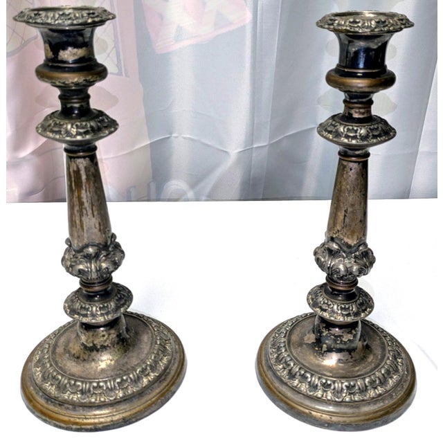 An elegant pair of antique Victorian-era silverplate candlesticks featuring richly detailed Rococo Revival ornamentation...