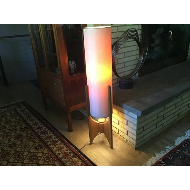 This unusual midcentury modern floor lamp combines a cylindrical fabric shade with three wood legs and brass trim. The...