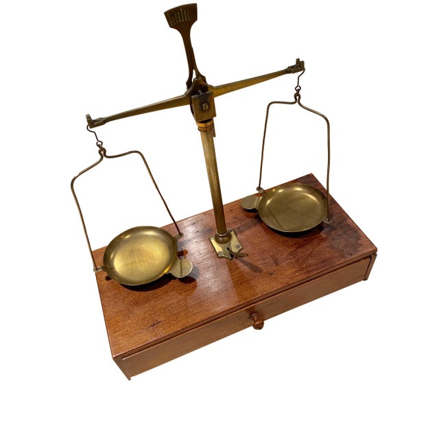 A 19th century brass hanging scale on a wooden base with one drawer and with weights from France.