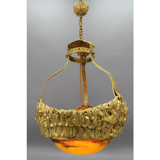 This impressive French Art Deco chandelier features an ornate brass frame in the shape of a nest, on the sides depicting...