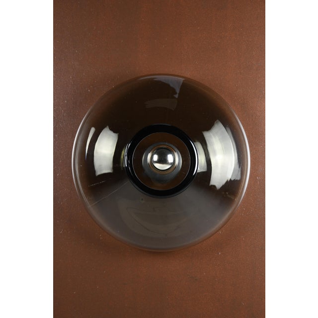 A pair of “bot” wall lamps — giusto toso for leucos, murano, 1971 twin discs of smoked murano glass, each glowing around a...