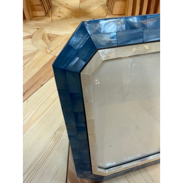 Elegant picture frame featuring a hand-applied mosaic of iridescent blue and ivory mother-of-pearl tiles. The wide,...