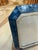 Elegant picture frame featuring a hand-applied mosaic of iridescent blue and ivory mother-of-pearl tiles. The wide,...