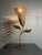 A sculptural table lamp in the form of a stylized tulip, entirely hand-woven in rattan and wicker over a wire armature....