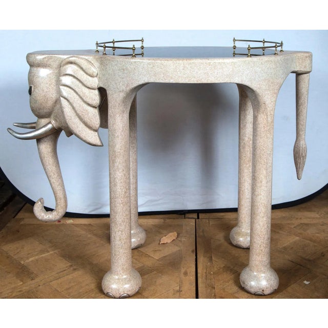 Marge Carson elephant rolling bar cart or table. Made of composition wood with a tinted glass top and brass rails.