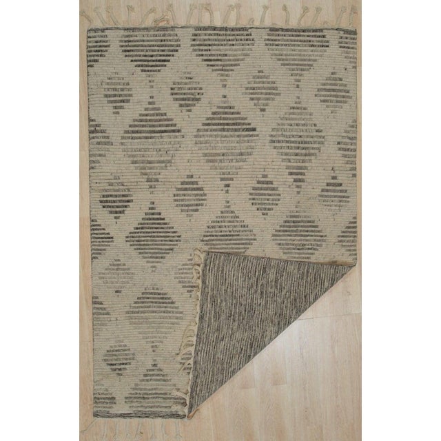 This hand knotted pile rug features a primary color palette of ivory, beige, and cream white, crafted from high-quality...