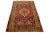 A vintage Anatolian rug, hand-knotted, featuring a geometric design displayed on a red field, bordered by yellow sections,...