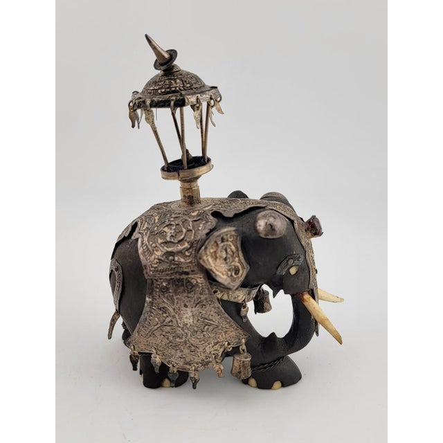 The product is a rare antique Indian ebony silver overlay jeweled elephant with real ruby stones. This intricate carving...