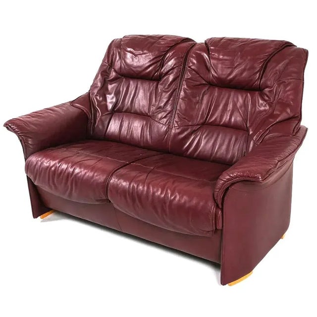 A mid century transitional modern Scandinavian leather loveseat in a burgundy red. The loveseat is well constructed,...