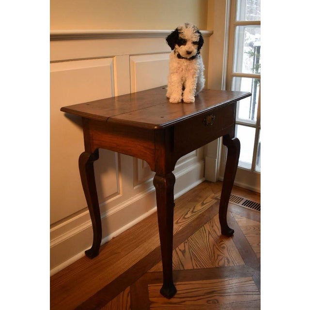 An enchanting dark oak English country Queen Anne lowboy or dressing table from the early 1700s. A rich patina covers the...