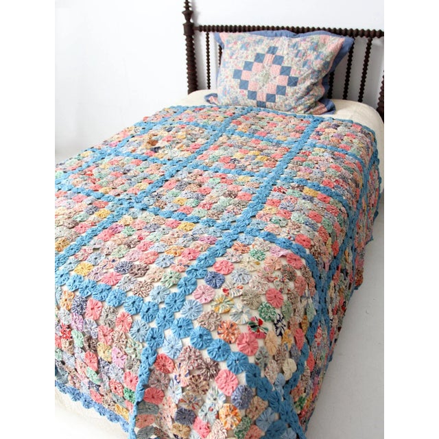 Antique yo-yo quilt dating to the 1920s–1940s, showcasing a charming patchwork design created from colorful fabric circles...