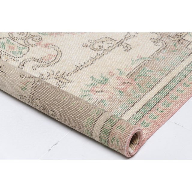 This is a vintage Turkish Oushak rug from the Mid 20th Century. The piece was hand-knotted.