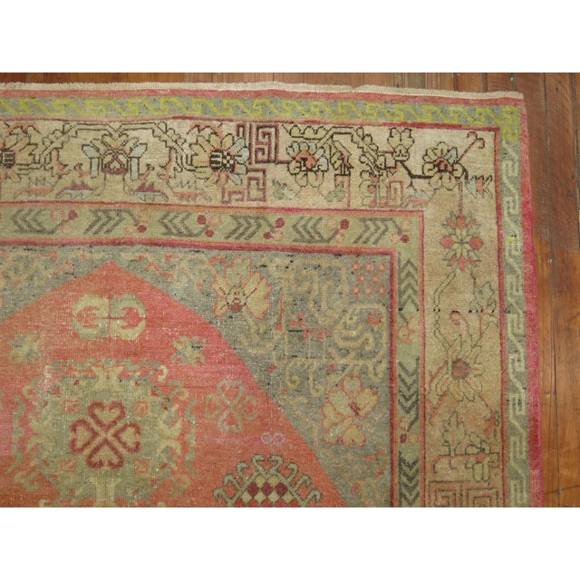 One-of-a-kind early 20th century Khotan rug with a soft pink field consisting of a yin yang pattern and a camel border....