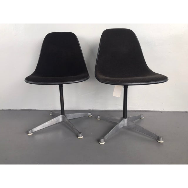 Pair of Herman Miller Eames swivel base office chairs. The chairs are in black fabric and are dated 1983. Labels and marks...