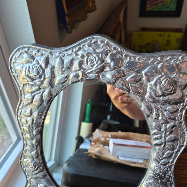 This handcrafted Mexican pewter tabletop mirror by Treasure Seekers showcases intricate folk art design with a rose motif....