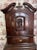 Petite dark oak cupboard in 2 parts. Lovely carving of man drinking from wine jug. on door. Scrolled urn pediment with...