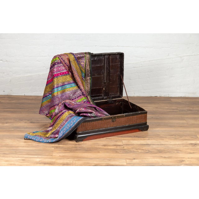A Chinese antique wooden treasure chest from the early 20th century with rattan accents and dark brass handles. This...