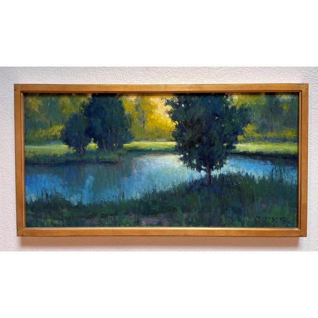 The artwork depicts a serene landscape, where vibrant green foliage contrasts with the shimmering gold light of the...