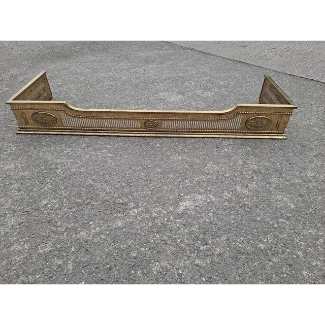 An elegant Regency-style pierced brass fireplace fender, featuring classical detailing and a beautifully proportioned low-...