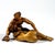 Crouching faun kneeling on one leg with outstretched arms, holding an apple in his right hand and looking to the side with...