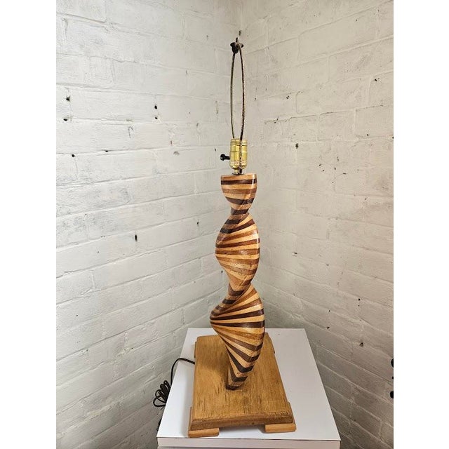Mid-Century Modern twisted spiral lamp. This sculptural lamp has a helix-shaped wooden base, crafted from alternating...