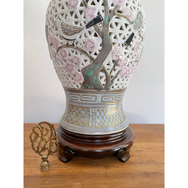 Beautiful pierced urn table lamp on an Asian wooden base. Lamp is decorated on all sides with cherry blossoms and branches...