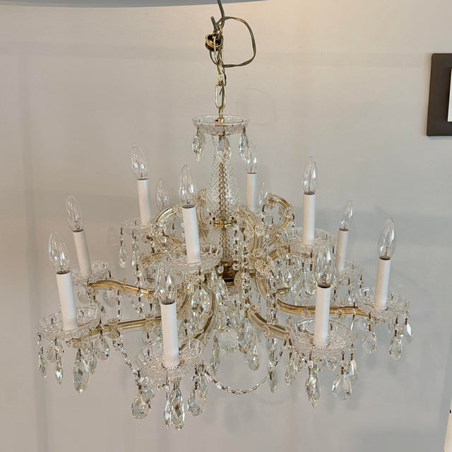 Traditional Maria Theresa style crystal chandelier, often featuring a gold finish and glass arms decorated with strands of...