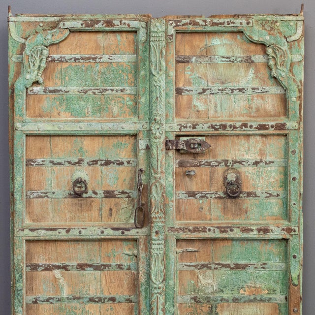 Pair of traditional carved doors from Rajasthan painted on the front in a light mint green. They have been joined together...