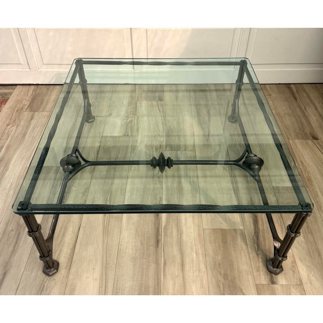 A striking late 20th-century iron and glass coffee table in the manner of Diego Giacometti, featuring a sculptural metal...