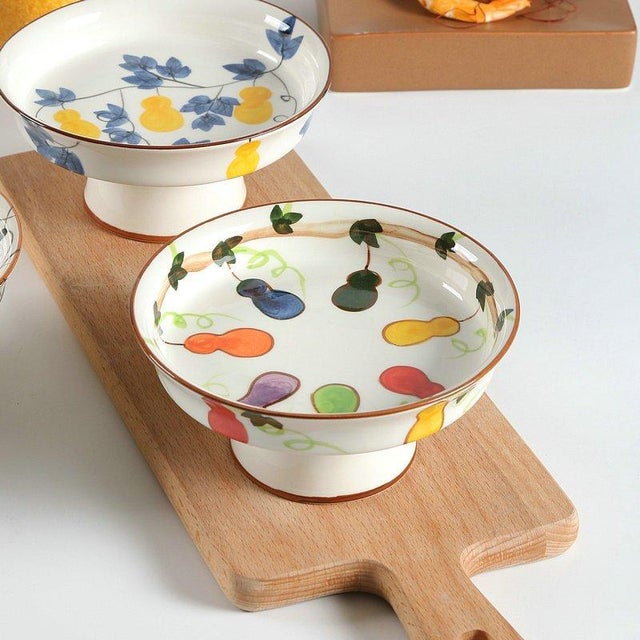 This is a three-piece set of ceramic fruit stands featuring a shallow dish atop a raised base. The interior of each dish...
