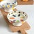 This is a three-piece set of ceramic fruit stands featuring a shallow dish atop a raised base. The interior of each dish...