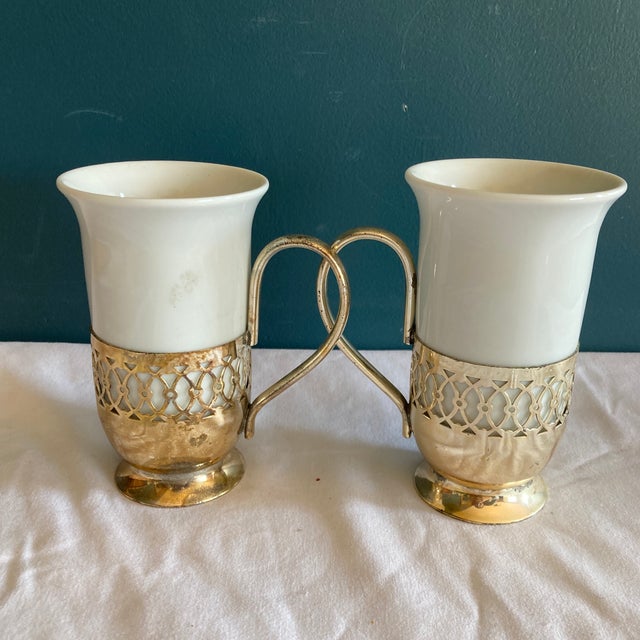 A lovely pair of vintage porcelain mugs featuring classic green shamrock motifs, each set within an elegant silver lattice...