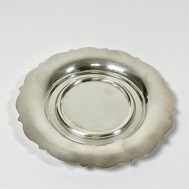 This Silver-plated wine coaster is from Oneida Silversmith out of the Mid-Century. It features two ridges of circles on...
