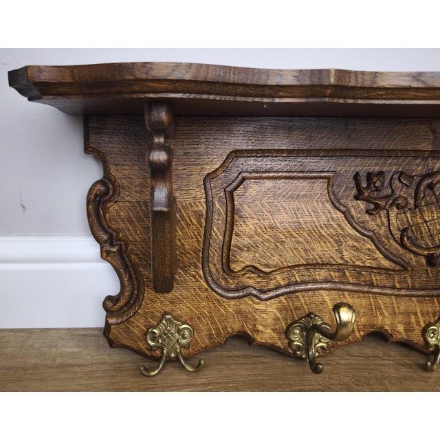 A beautifully crafted Vintage French coat hanger featuring rich oak tones and intricate carved detailing across the front...