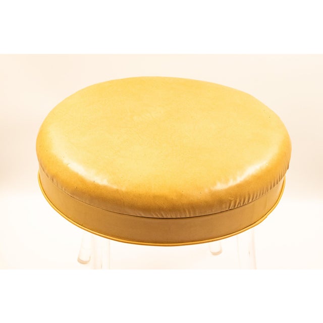 Round swivel seat on four splayed solid lucite legs, each leg thick and gently tapered, angled outward for stability and...