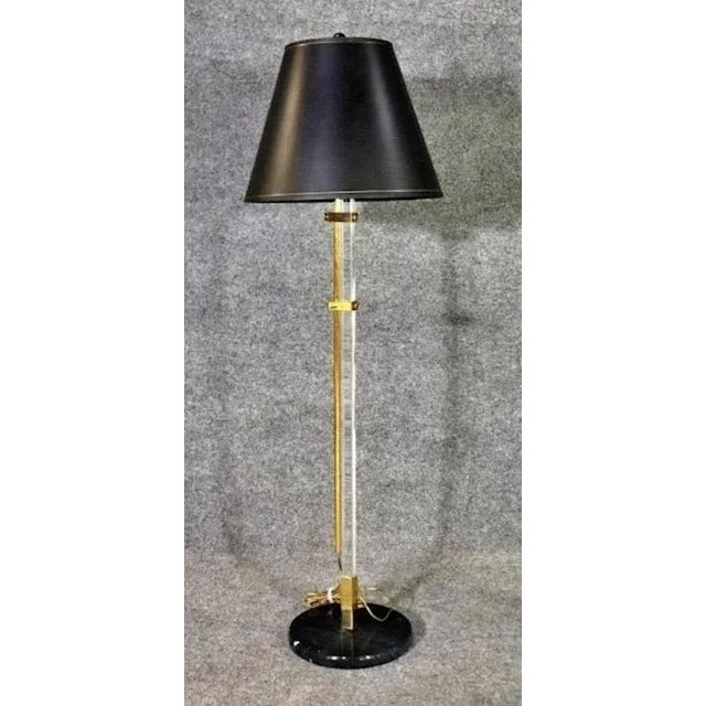 Adjustable floor lamp with polished brass and clear lucite, set on a black marble base, with black and gold shade. Base:...