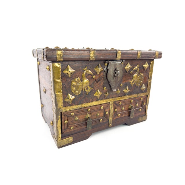 A striking mid‑century Indian jewelry chest crafted in dense rosewood and decorated with hand‑worked brass mounts and...
