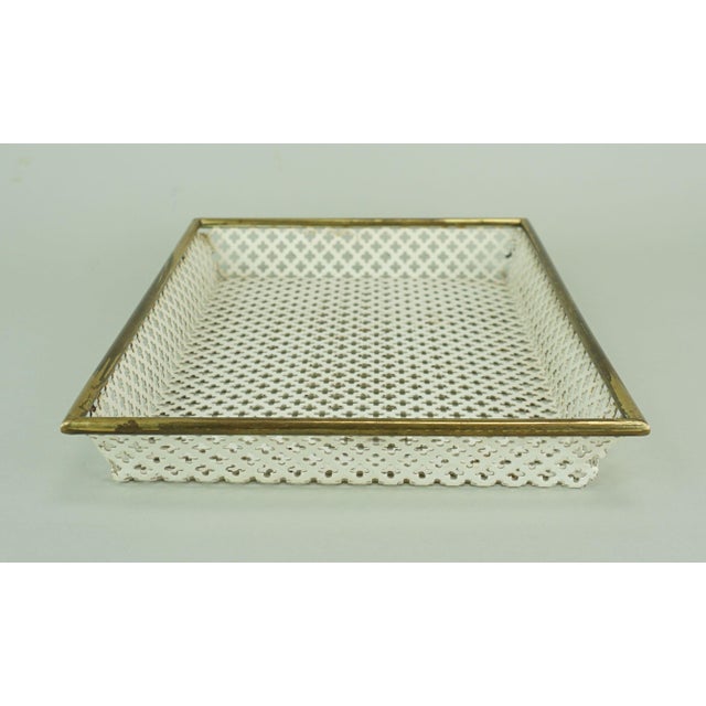 A 1950s tray in a minimalist, purist design. Made of white lacquered perforated metal with a brass rim. The design is...
