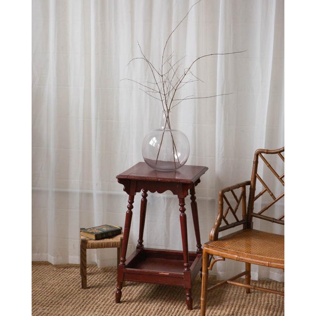 This charming antique side table has great character, with its original deep red paint, turned legs, and a sweet lower...