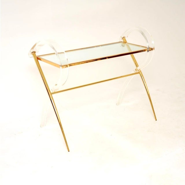 A stunning vintage Italian acrylic glass and gold finish console table, dating from the 1970’s. It has a very decorative...