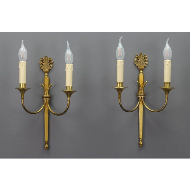 Pair of French Art Deco brass twin arm sconces from ca. 1930. This elegant pair of brass sconces has a beautiful brass...