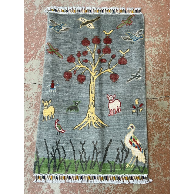 Nature pictorial rug, hand-knotted in Afghanistan from 100% wool. Measuring 2’ x 3’1”, the rug features a charming nature-...